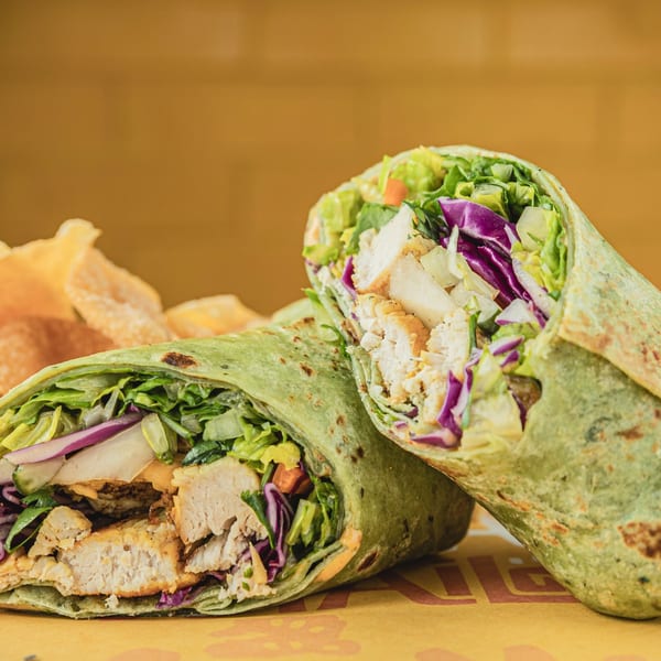 Two Thai chicken wraps, cut in half, filled with chicken, lettuce, red cabbage, and sauce.