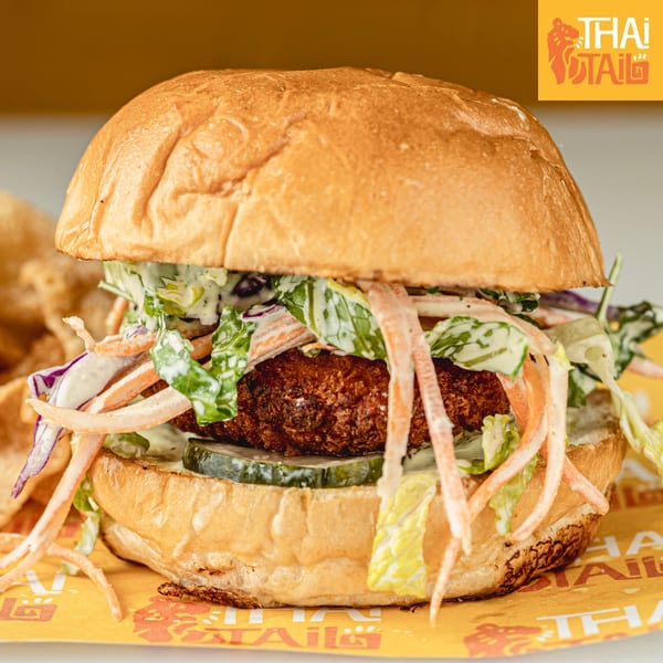 Thai Tail's crispy chicken sandwich with coleslaw and pickles on a brioche bun.